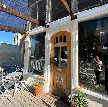 Café Coco storefront at 24 W Main Ave in downtown Spokane — arched wooden door numbered 24, COCO sign on the brick, sidewalk tables